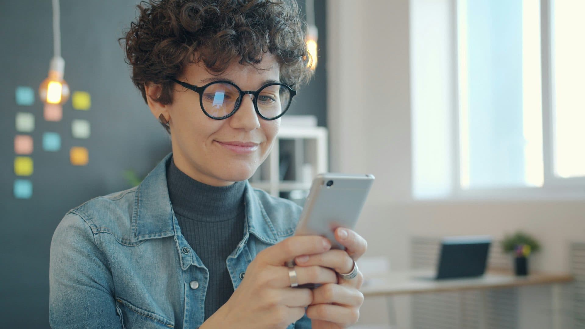 Pessoa sorrindo enquanto troca mensagem pelo WhatsApp no celular